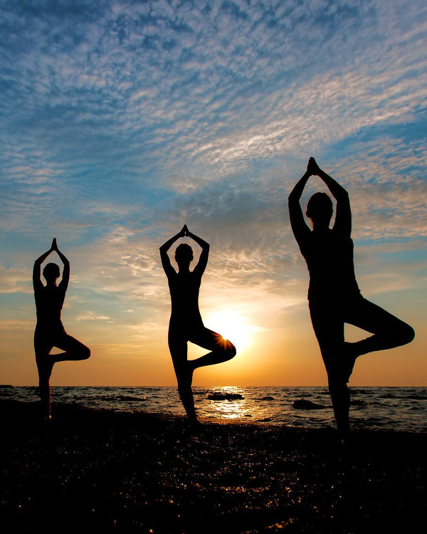 Three people doing Tree Yoga Pose on the Beach at Sunrise.